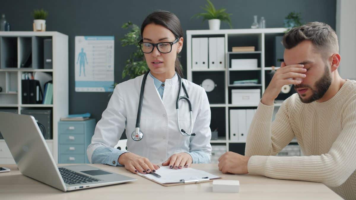 Patient se tenant le front pendant une consultation avec une praticienne, illustrant la prise en charge d'un patient sujet aux vertiges.
